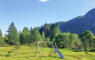 a playground with two swings in a field at Three-Bedroom Holiday Home In Vikanes in Eiknes