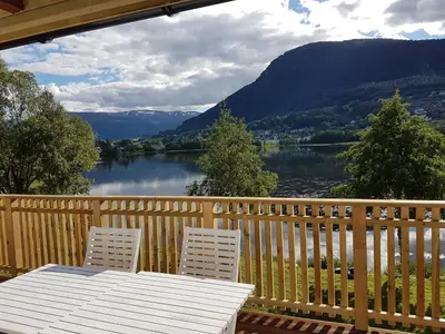 a table and two chairs on a deck with a view of a lake at Voss Interlake - Villa in Skulestadmo