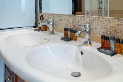 a bathroom sink with two faucets and a mirror at Prize by Radisson, Xhibition Bergen City in Bergen