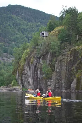 two people are in kayaks on a river at Rongen gard in Bolstadøyri