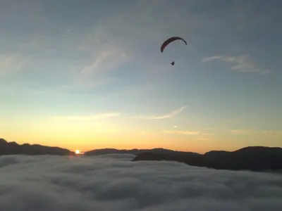 a kite flying in the sky above the clouds at Rongen gard in Bolstadøyri