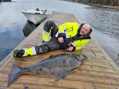 a man laying on a dock with a large fish at Holiday Home Kvernesfjorden in Averoy