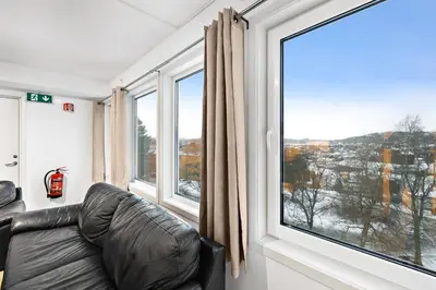 a leather couch in a room with a large window at Namsos Hybelhus in Namsos