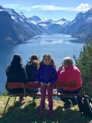 a group of people sitting on a bench overlooking a lake at Fjord View Apartment in Stranda