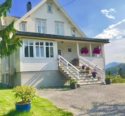 a white house with flowers on the front porch at Fjord View Apartment in Stranda