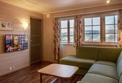 a living room with a couch and a table and windows at Birkebeineren Hotel & Apartments in Lillehammer