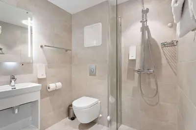 a bathroom with a shower and a toilet and a sink at Bergen Harbour Hotel, WorldHotels Crafted in Bergen