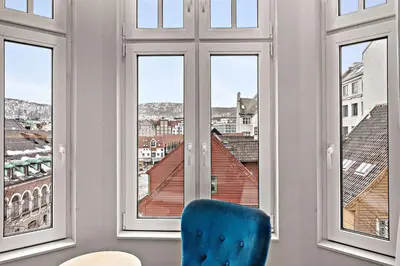 a blue chair sitting in a room with windows at Bergen Harbour Hotel, WorldHotels Crafted in Bergen