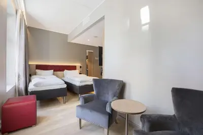 a room with two beds and a chair and a table at Bergen Harbour Hotel, WorldHotels Crafted in Bergen