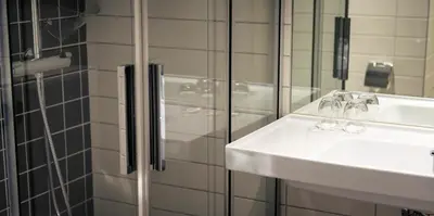 a bathroom with a sink and a glass shower at Home Hotel Hammer in Lillehammer