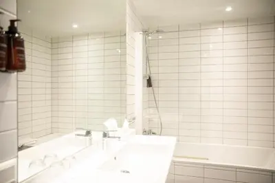 a white bathroom with a tub and a sink at Home Hotel Hammer in Lillehammer
