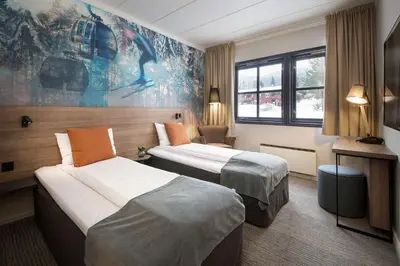 a hotel room with two beds and a desk at Scandic Hafjell in Hafjell