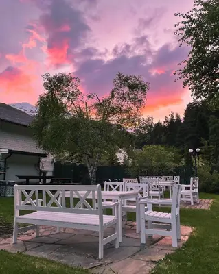 a row of white benches in a yard with a sunset at Valldal Fjord Lodge B&B in Valldal