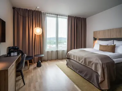 a hotel room with a bed and a desk and a window at Quality Airport Hotel Værnes in Stjoerdal