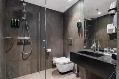 a bathroom with a shower and a toilet and a sink at Clarion Hotel Admiral in Bergen