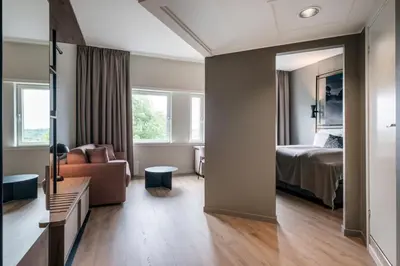 a room with a bed and a couch and a mirror at Quality Hotel Edvard Grieg in Bergen