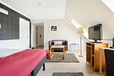 a bedroom with a bed and a flat screen tv at Best Western Plus Hotel Bakeriet in Trondheim