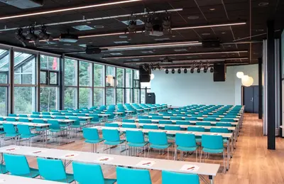 an empty lecture hall with blue chairs and tables at Thon Hotel Bergen Airport in Bergen