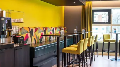 a restaurant with a bar with yellow walls and chairs at Thon Hotel Bergen Airport in Bergen