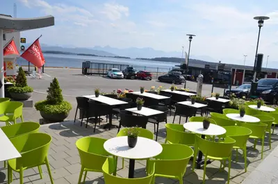 a row of tables and green chairs on a patio at Thon Hotel Moldefjord in Molde