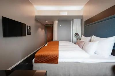 a bedroom with a large bed and a flat screen tv at Clarion Hotel Bergen Airport in Bergen