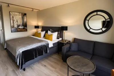 a bedroom with a bed and a couch and a mirror at Klækken Hotel in Hønefoss