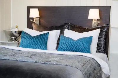a bed with blue and white pillows on it at Klækken Hotel in Hønefoss