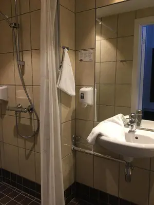 a bathroom with a sink and a shower with a mirror at Klækken Hotel in Hønefoss