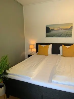a large bed with white sheets and yellow pillows at Vikingskipet Hotell in Hamar