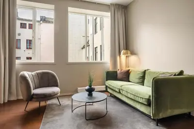 a living room with a green couch and a chair at Home Hotel Bryggen in Bergen