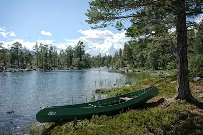 a green canoe sitting on the shore of a lake at Herangtunet Mountain Lodge in Heggenes