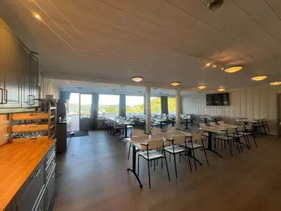 a dining room with tables and chairs and windows at Gjøvik Hovdetun Hostel in Gjøvik