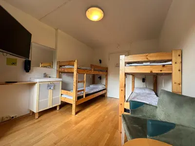 a room with two bunk beds and a couch at Gjøvik Hovdetun Hostel in Gjøvik