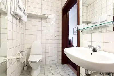 a white bathroom with a toilet and a sink at Chesterfield Hotel in Trondheim