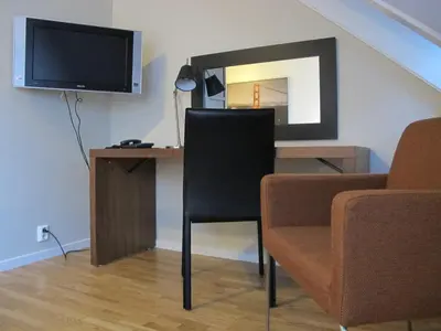 a room with a desk with a television and a chair at Chesterfield Hotel in Trondheim