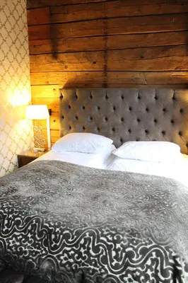a bedroom with a large bed with a wooden wall at Det Hanseatiske Hotel in Bergen