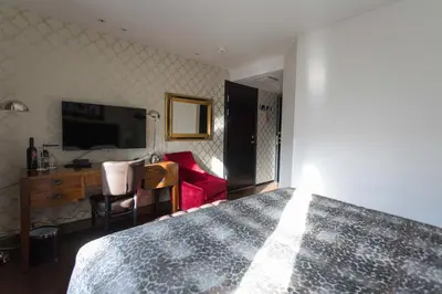 a bedroom with a bed and a desk and a tv at Det Hanseatiske Hotel in Bergen