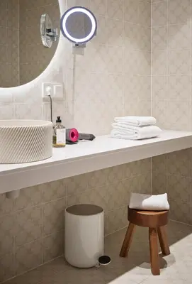 a bathroom with a sink and a mirror and a stool at Hotel 1904 in Ålesund