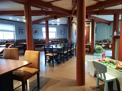 a restaurant with wooden columns and tables and chairs at Hafjell Hotell in Hafjell