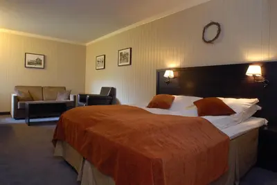 a hotel room with a large bed and a chair at Hafjell Hotell in Hafjell