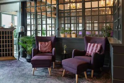 a lobby with two chairs and a table and windows at Home Hotel Grand Gjøvik in Gjøvik