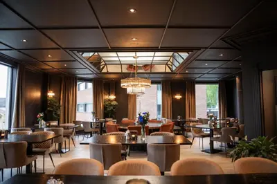 a restaurant with tables and chairs and windows at Home Hotel Grand Gjøvik in Gjøvik