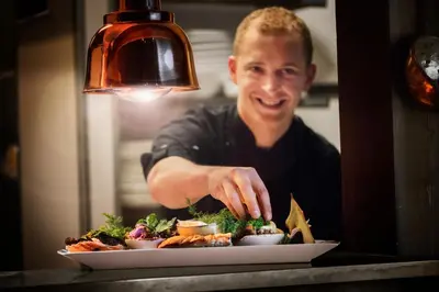 a man preparing a plate of food on a table at Flåmsbrygga Hotel in Flåm