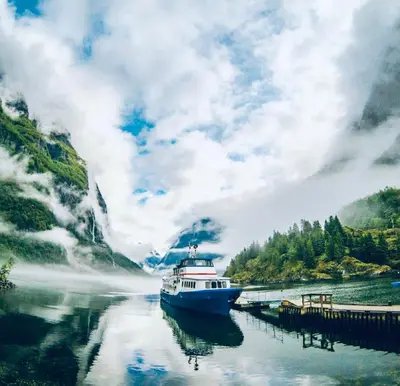 a boat is docked at a dock on a river at Gudvangen Fjordtell in Gudvangen
