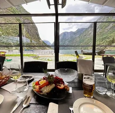 a table with a plate of food and a glass of beer at Gudvangen Fjordtell in Gudvangen