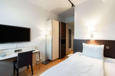 a hotel room with a bed and a desk and a tv at Scandic Alexandra Molde in Molde