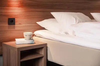 a bed with a coffee cup on a night stand next to a bed at Thon Hotel Otta in Otta
