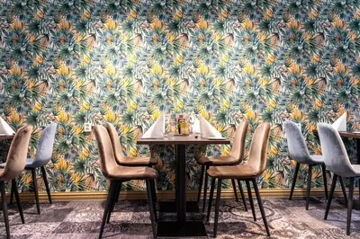 a restaurant with a table and chairs in front of a floral wallpaper at Thon Hotel Otta in Otta