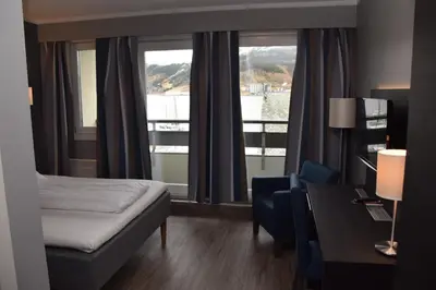 a hotel room with a bed and a desk and window at Thon Hotel Måløy in Måløy