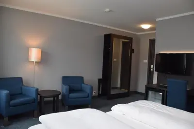a hotel room with a bed and two chairs and a television at Thon Hotel Måløy in Måløy